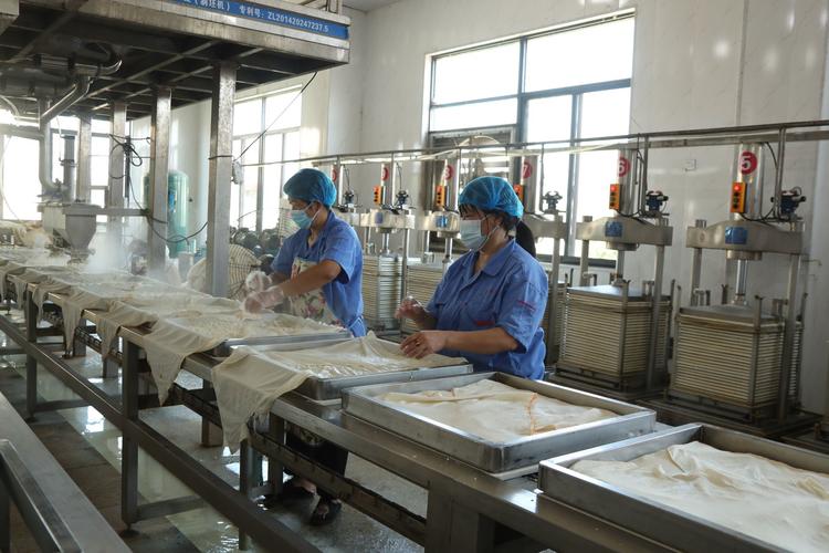 图为明侯故里食品有限责任公司生产车间内,工人师傅正在制作豆干.